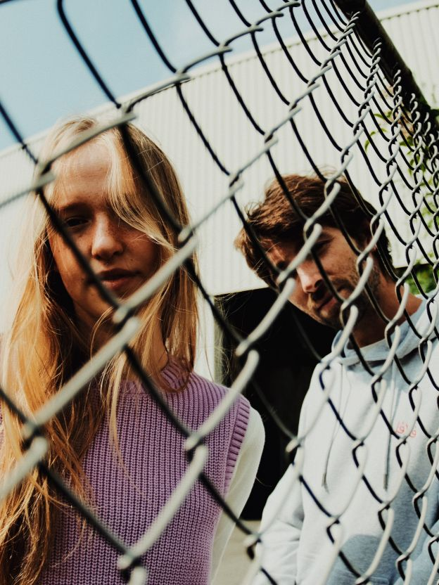 Two boys and one girl on the beach wearing light and natural white, blue and beige colored basic t-shirts and shorts