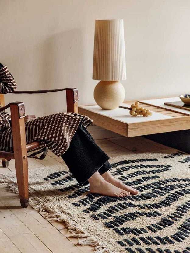 Home textiles - A woman sitting in a chair with bare feet on a Finarte carpet