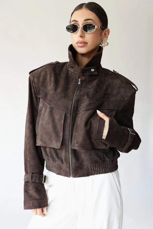Person wearing a brown suede jacket on a white background