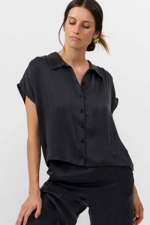 Woman wearing a black sleeveless blouse against a white background