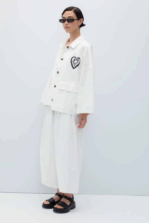 Person wearing a white outfit with a heart design on a plain background