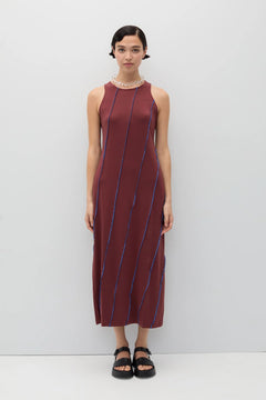 Woman wearing a maroon dress with blue stripes against a white background