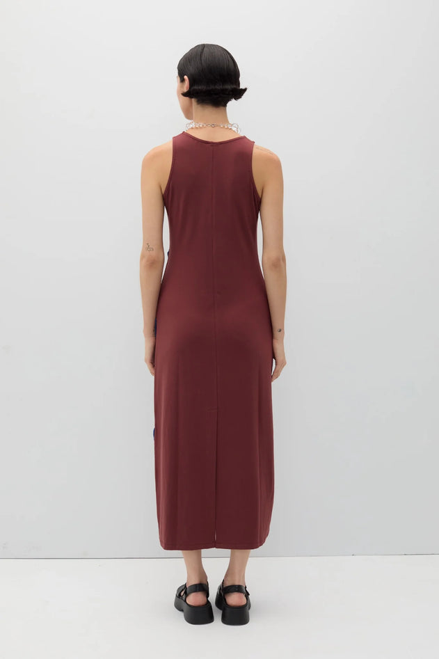Person wearing a burgundy sleeveless dress against a white background