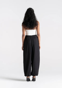 Woman wearing a white top and black high-waisted pants on a white background