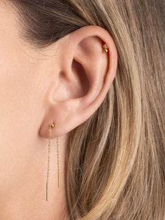 Close-up of an ear wearing gold earrings with a blurred background