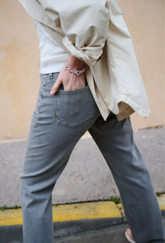 Person wearing a beige jacket and gray jeans with a blurred background