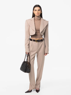 Woman wearing a beige suit with a black handbag on a white background