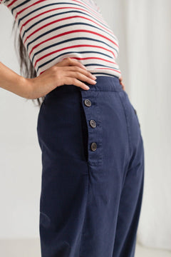 Person wearing a striped shirt and navy pants with a blurred background