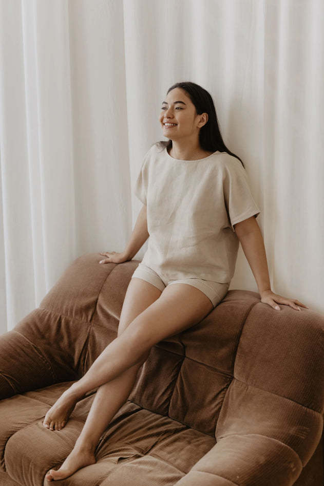 Woman sitting on a brown couch against a white curtain