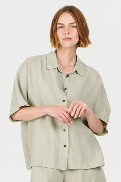 Woman wearing a light green shirt and pants on a white background