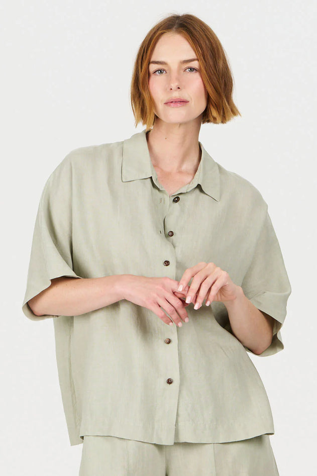 Woman wearing a light green shirt and pants on a white background