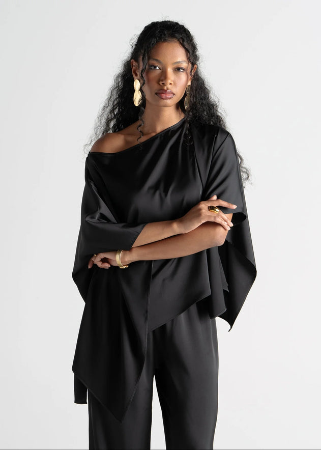 Woman wearing a black off-shoulder top and pants against a white background