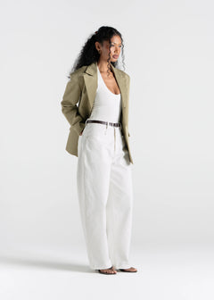 Woman wearing a green jacket and white pants on a white background