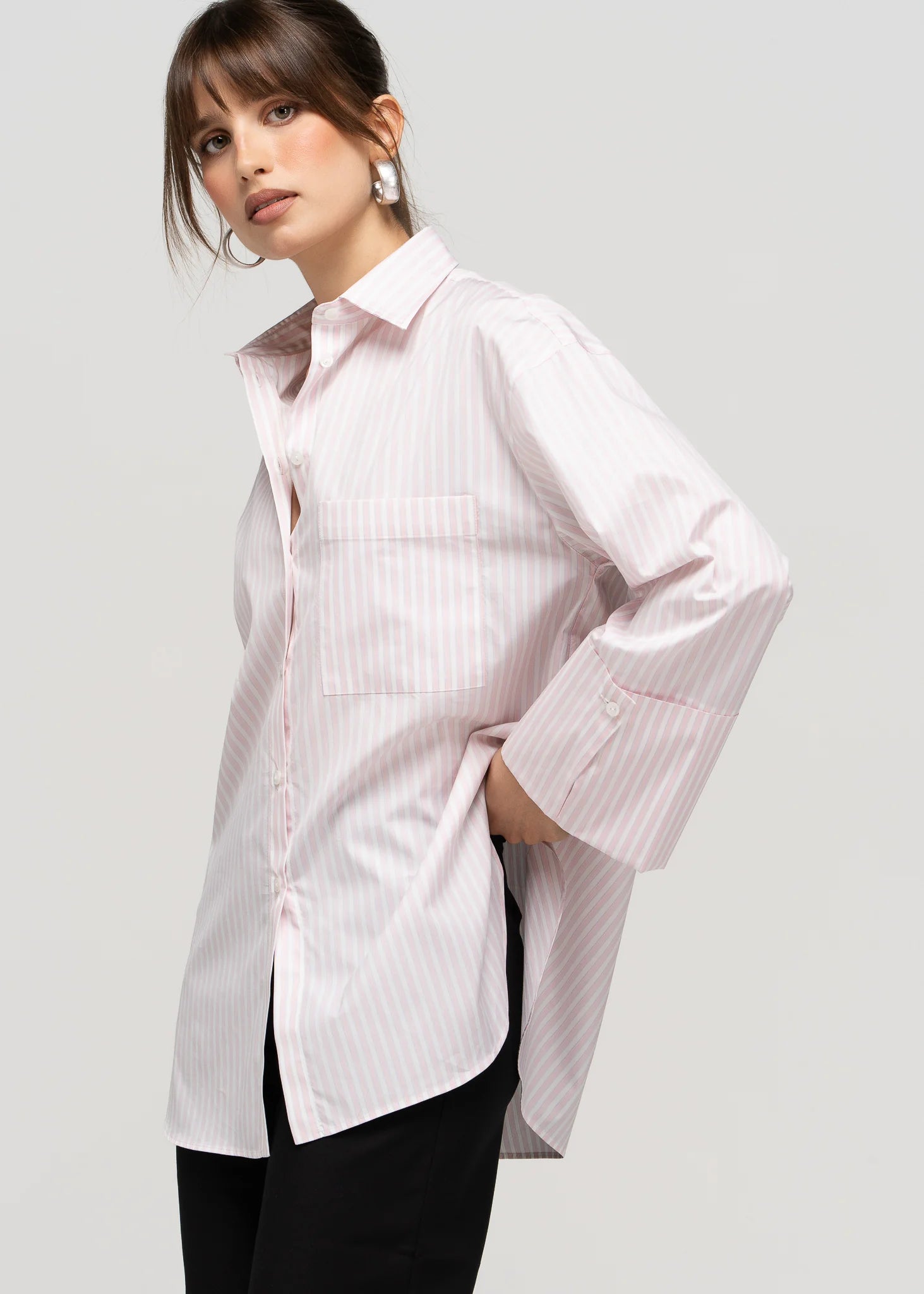 Woman wearing a white button-up shirt with a subtle pattern on a plain background