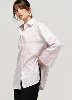 Woman wearing a white button-up shirt with a subtle pattern on a plain background