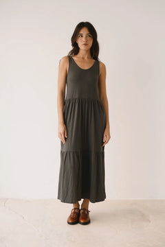 Woman wearing a dark green dress standing against a white background
