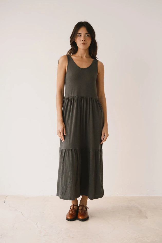 Woman wearing a dark green dress standing against a white background