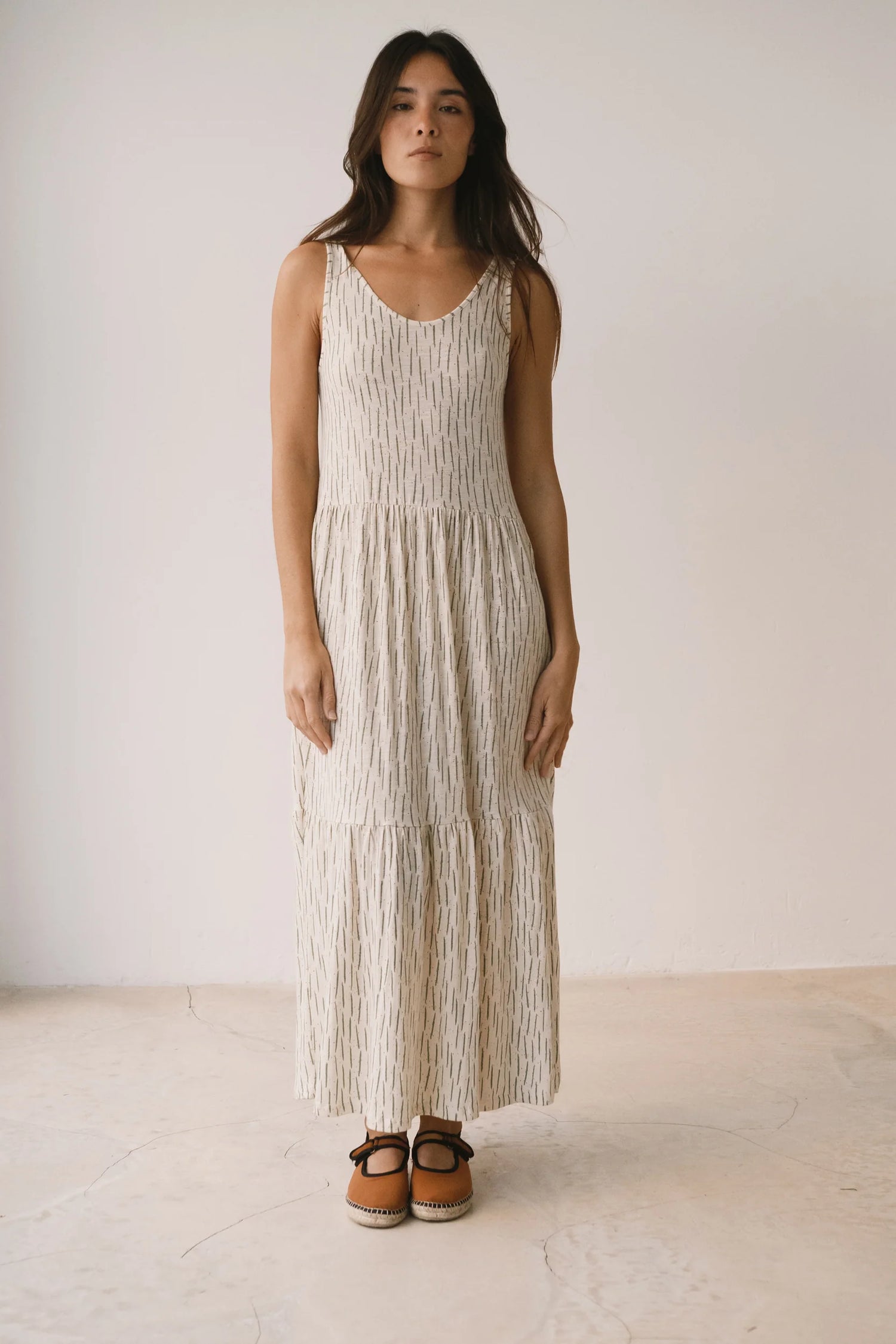 Woman wearing a long, light-colored dress with a white background