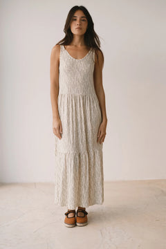 Woman wearing a long, light-colored dress with a white background