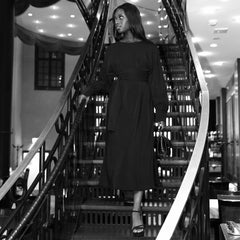 Woman in a black dress standing on a staircase in a stylish interior setting