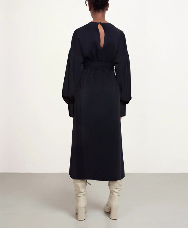 Person wearing a long black dress with a cutout back on a white background