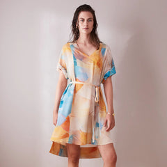 Woman wearing a colorful dress with abstract patterns on a plain background