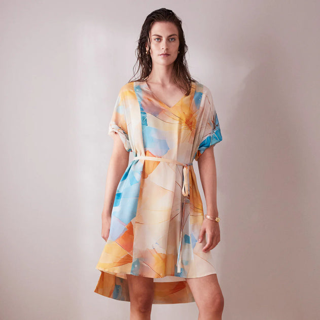 Woman wearing a colorful dress with abstract patterns on a plain background