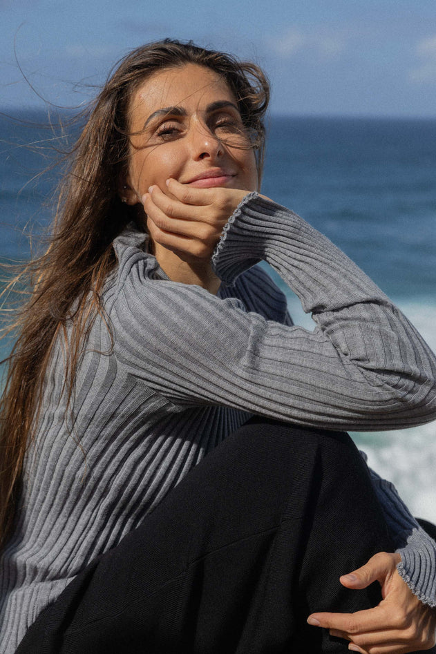 Woman sitting by the ocean with a blue sky background