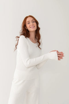 Woman wearing a white ribbed dress against a plain background