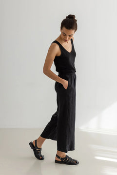 Woman wearing a black sleeveless top and wide-leg pants on a white background