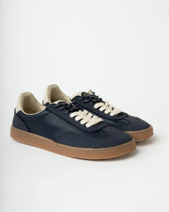 Pair of navy blue sneakers with white laces on a light gray background