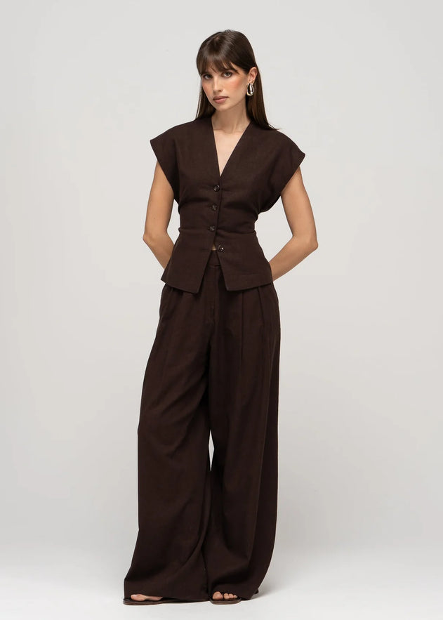 Woman wearing a brown suit with wide-leg pants on a white background