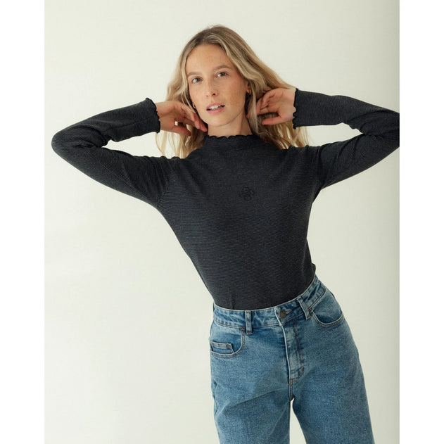 Woman wearing a black sweater and blue jeans against a white background
