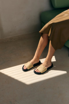 Person wearing woven sandals on a sunlit floor