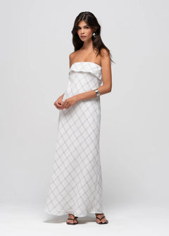 Woman wearing a white strapless dress with a geometric pattern on a plain background