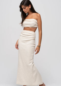 Woman wearing a white strapless top and skirt set on a light gray background