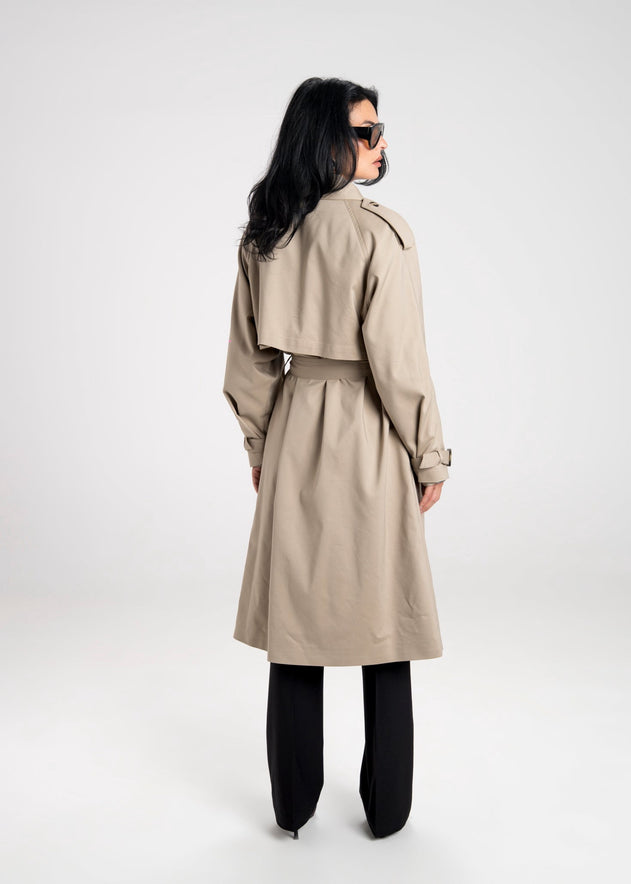 Person wearing a beige trench coat on a white background