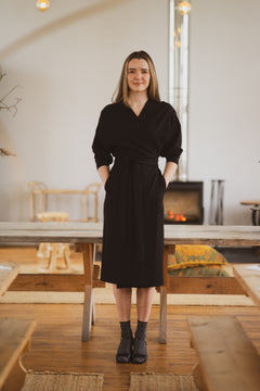 Woman in a black dress standing in a modern living room.