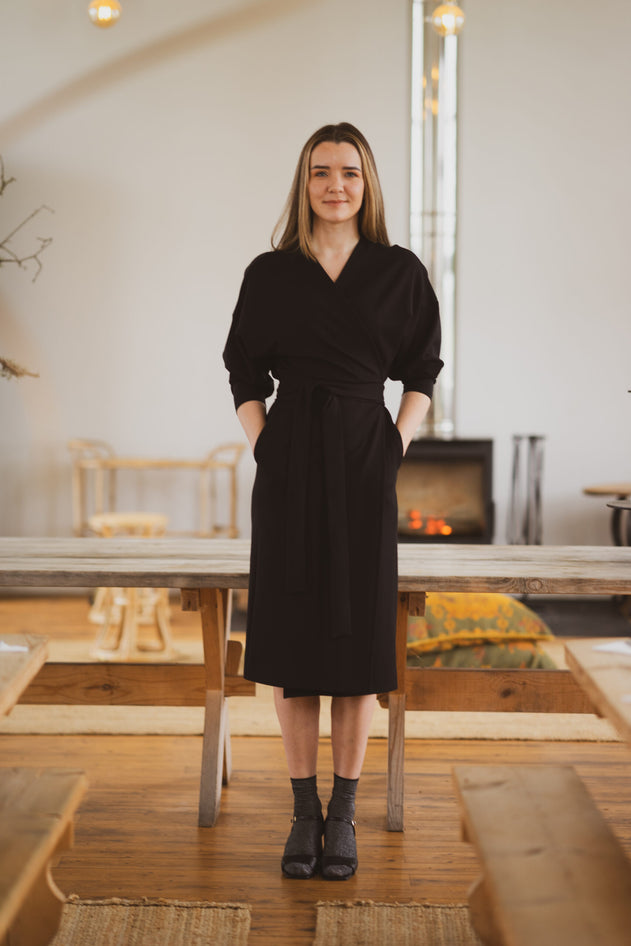 Woman in a black dress standing in a modern living room.