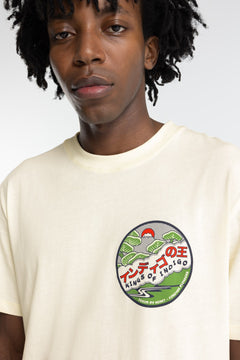 Person wearing a cream t-shirt with a graphic design on a plain background