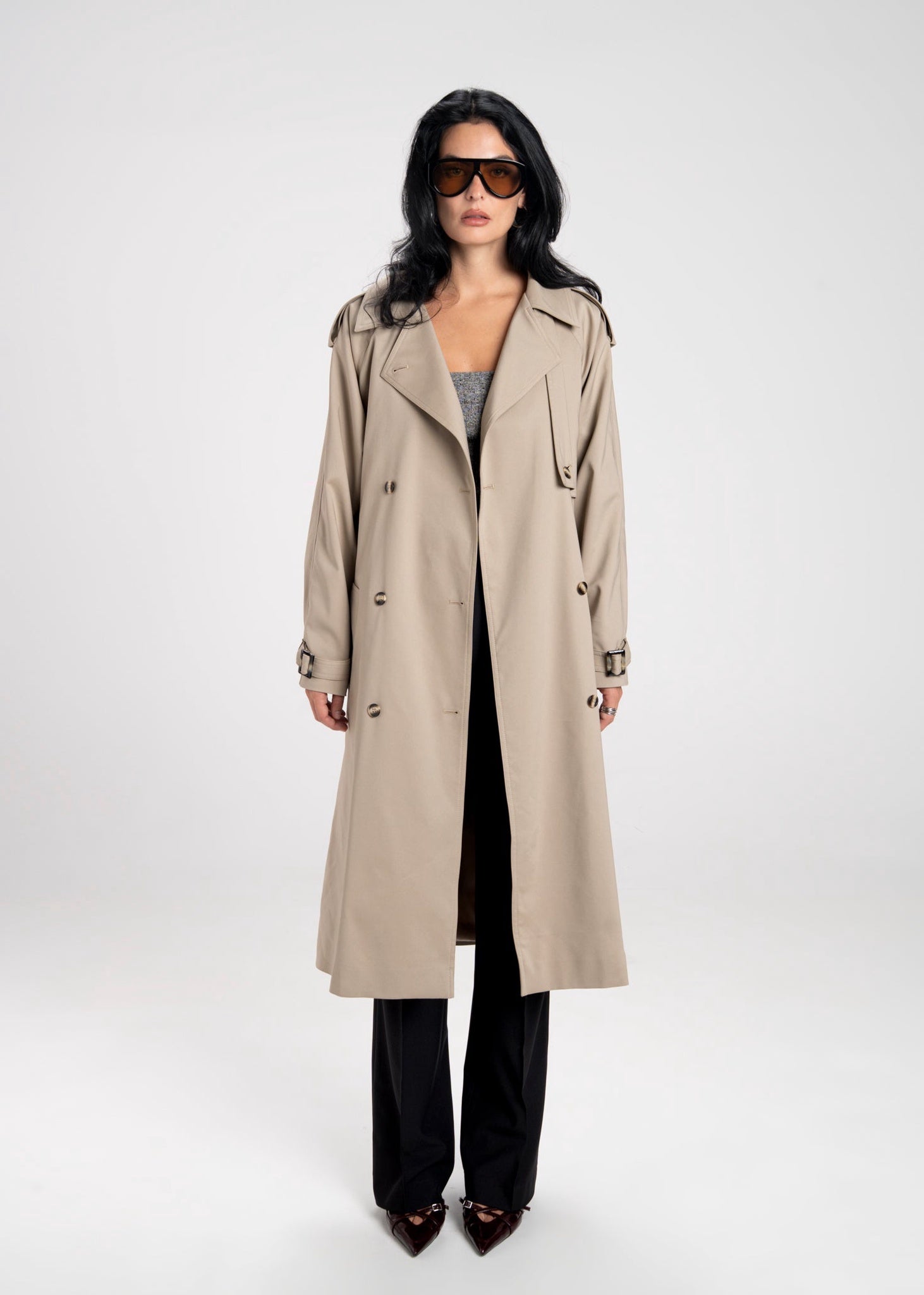 Woman wearing a beige trench coat on a white background